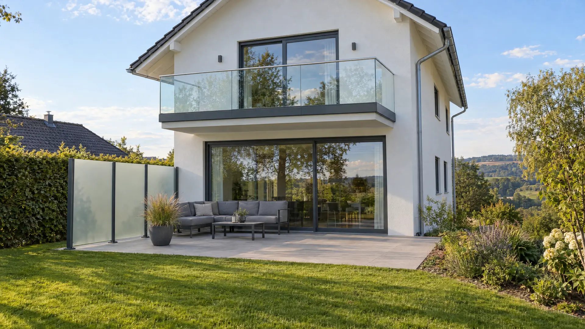 Wohnhaus mit Balkonbrüstung aus Glas, großer Glasschiebetür zur Terrasse und Sichtschutz aus satiniertem Glas