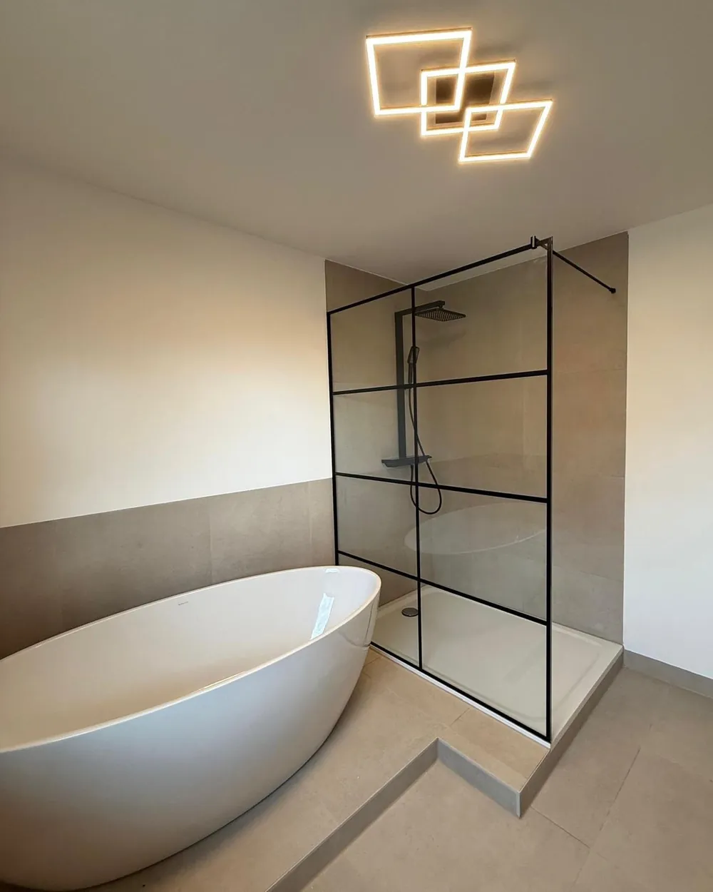 Walk-in-Glasdusche im Loft-Style mit schwarzem Rahmen neben freistehender Badewanne