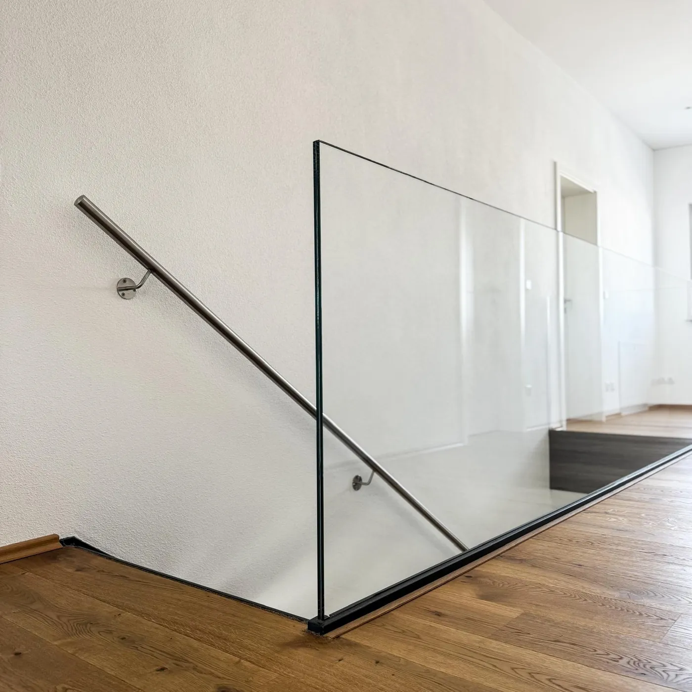 Glasgeländer an einer Innentreppe mit Holzstufen und Edelstahl-Handlauf